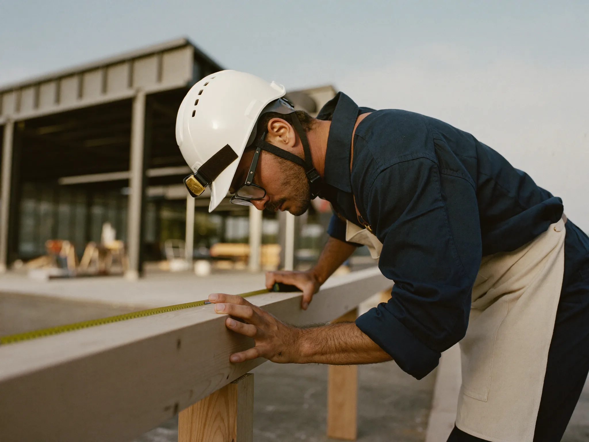 A skilled Australian carpenter measuring a hardwood beam on a Melbourne construction site at golden hour